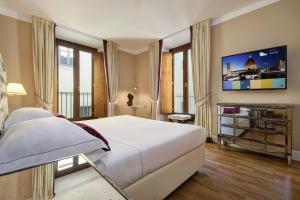 - une chambre avec un grand lit blanc et une télévision dans l'établissement Grand Hotel Cavour, à Florence