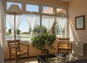 a living room with windows and a table and chairs at Hosteria Solar de la Costa in Puerto Madryn