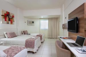 a hotel room with two beds and a desk with a laptop at GOLD MARTAN HOTEL in Belém