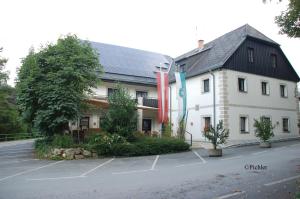 un grand bâtiment blanc avec un toit noir dans l'établissement Schlosstaverne Thannhausen, à Weiz