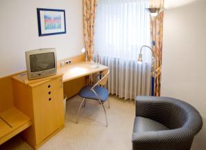 a room with a desk with a tv and a chair at Hotel Haus Appel in Rech