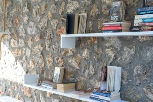 a book shelf with books on it next to a stone wall at Mouras Resort in Livadi Astypalaias