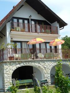 ein Gebäude mit einem Balkon mit Sonnenschirmen darauf in der Unterkunft House Sophie in Vonyarcvashegy