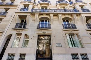 un bâtiment avec une porte dorée et des balcons. dans l'établissement Résidence Charles Floquet, à Paris