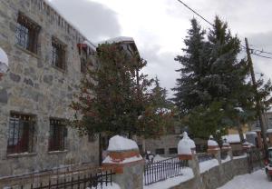 a building with a christmas tree next to a fence at Archontiko Koziakas in Palaios Agios Athanasios