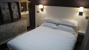 una camera da letto con un grande letto bianco con cuscini bianchi di Auberge du cheval blanc ad Ajaccio