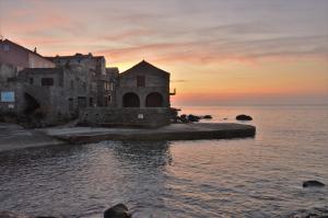 an old building on the water with a sunset in the background at La Marine in Luri