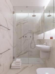 a white bathroom with a shower and a sink at The Moorgate by COVE in London