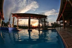 a swimming pool with a gazebo and the sunset at Kierieklapper in Hectorspruit