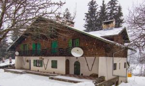 a house with a clock on it in the snow at Charming Chalet Timisu de Sus in Predeal +15 photos