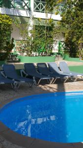 eine Gruppe von Stühlen neben einem Pool in der Unterkunft TERRAZAS DEL CARIBE, APARTA HOTEL. in Santo Domingo