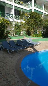 eine Gruppe von Liegestühlen neben einem Pool in der Unterkunft TERRAZAS DEL CARIBE, APARTA HOTEL. in Santo Domingo