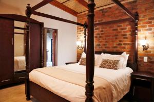 a bedroom with a four poster bed and a brick wall at Kierieklapper in Hectorspruit