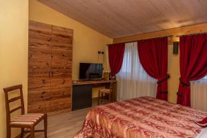 sypialnia z łóżkiem, czerwonymi zasłonami i biurkiem w obiekcie Hotel Chaberton w mieście Cesana Torinese