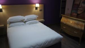 a bedroom with a white bed and a dresser at Auberge du cheval blanc in Ajaccio