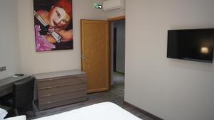 une chambre avec une télévision et un tableau sur le mur dans l'établissement Auberge du cheval blanc, à Ajaccio