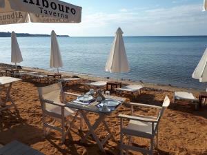a table with chairs and umbrellas on a beach at Albouro Seafront Apartments in Katelios