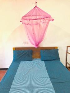ein Bett mit einem rosa Regenschirm darüber in der Unterkunft Sai Seashell Rest Inn Nilaveli in Trincomalee