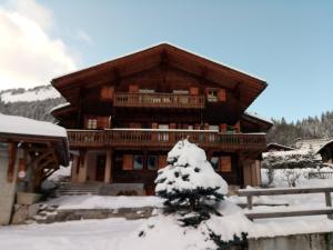 ein Blockhaus im Schnee mit einem Baum in der Unterkunft Chalet Beauroc in Morgins