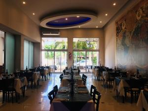 un comedor con mesas y sillas y una gran ventana en Atlas Grand Hotel Ituzaingo en Ituzaingó