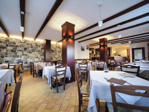 a restaurant with white tables and chairs and a stone wall at Ginepro d'Abruzzo in Casamaina