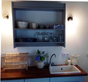 a kitchen with a sink and a shelf with dishes at Domaine Charente - Cottage Charente in Mazières