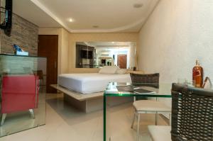 una habitación de hotel con una cama y una mesa y una habitación en Trópicos Motel, en Natal
