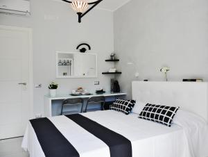 a white bedroom with a black and white bed and a desk at Costantino Suites in Sorrento