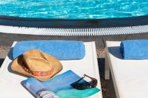 a hat and a book and sunglasses next to a swimming pool at Plus Fariones Apartamentos in Puerto del Carmen