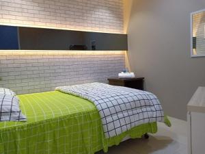 a bedroom with a bed with a green and white blanket at Derma Home Stay in Serpong