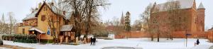 een met sneeuw bedekte straat met een gebouw en een kerk bij Hotel Pod Zamkiem in Olsztyn