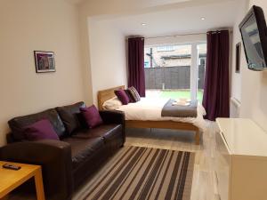 ein Wohnzimmer mit einem Sofa und einem Bett in der Unterkunft Leckhampton Road Apartments - Cheltenham in Cheltenham