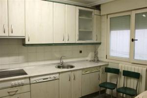 a kitchen with white cabinets and a sink and chairs at La Casa del Val in Valladolid