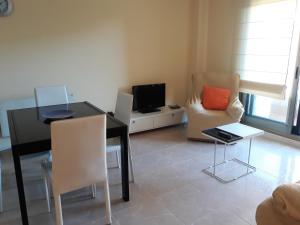 een woonkamer met een tafel, een tv en stoelen bij Piso de 3 Dormitorios en Noalla (Sanxenxo) in Noalla