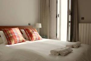 ein weißes Bett mit Handtüchern und einem Fenster in der Unterkunft La Casa del Val in Valladolid