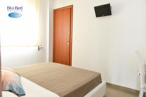 1 dormitorio con 1 cama y puerta con TV en Blu Bed Salento, en Torre Lapillo