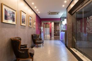 a hallway with chairs and paintings on the walls at Hotel Samasa Fundao in Fundão