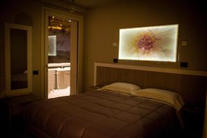 1 dormitorio con 1 cama y una pintura en la pared en Hotel Laghetto, en Prato Nevoso