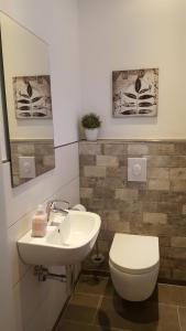 łazienka z umywalką i toaletą oraz 2 zdjęcia w obiekcie Emsdüne w mieście Oberlangen