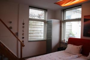 a bedroom with a bed and two windows at het Bakkershuisje in Colijnsplaat