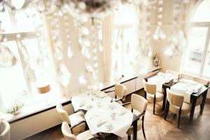 ein Restaurant mit Tischen und Stühlen in einem Zimmer mit Fenstern in der Unterkunft Heerens Hotel in Emden