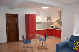 een keuken met rode kasten en een glazen tafel en stoelen bij Villa Jupe in Tías