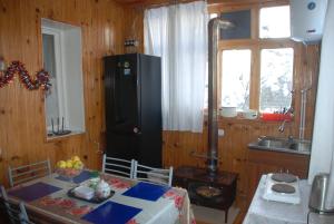 a kitchen with a table and a black refrigerator at Keti Pilpani Guesthouse in Mestia