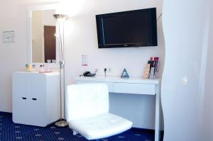 um quarto com uma cadeira branca e uma televisão na parede em Arthotel ANA Petite em Gersthofen