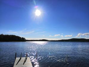 Muurame的住宿－Halkolanniemi，湖上的一个码头,阳光在天空中