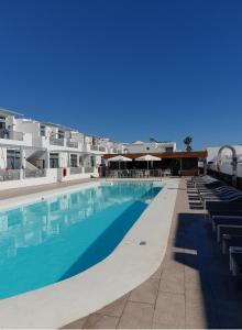 a large swimming pool with chairs and umbrellas at Los Gracioseros in Puerto del Carmen