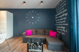 uma sala de estar com um sofá e um relógio na parede em Apartament Manufaktura em Lódź