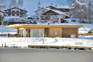 a house in the snow next to a body of water at Lakeside - 3.5 Zimmer Ferienwohnung am Laaxersee in Laax