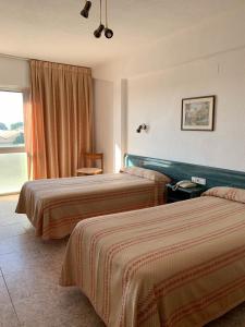 Villafranca de EbroにあるHotel Pepaのベッド2台と窓が備わるホテルルームです。