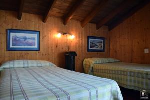 two beds in a room with wooden walls at Casa Rural El Puente in Cuevas del Becerro